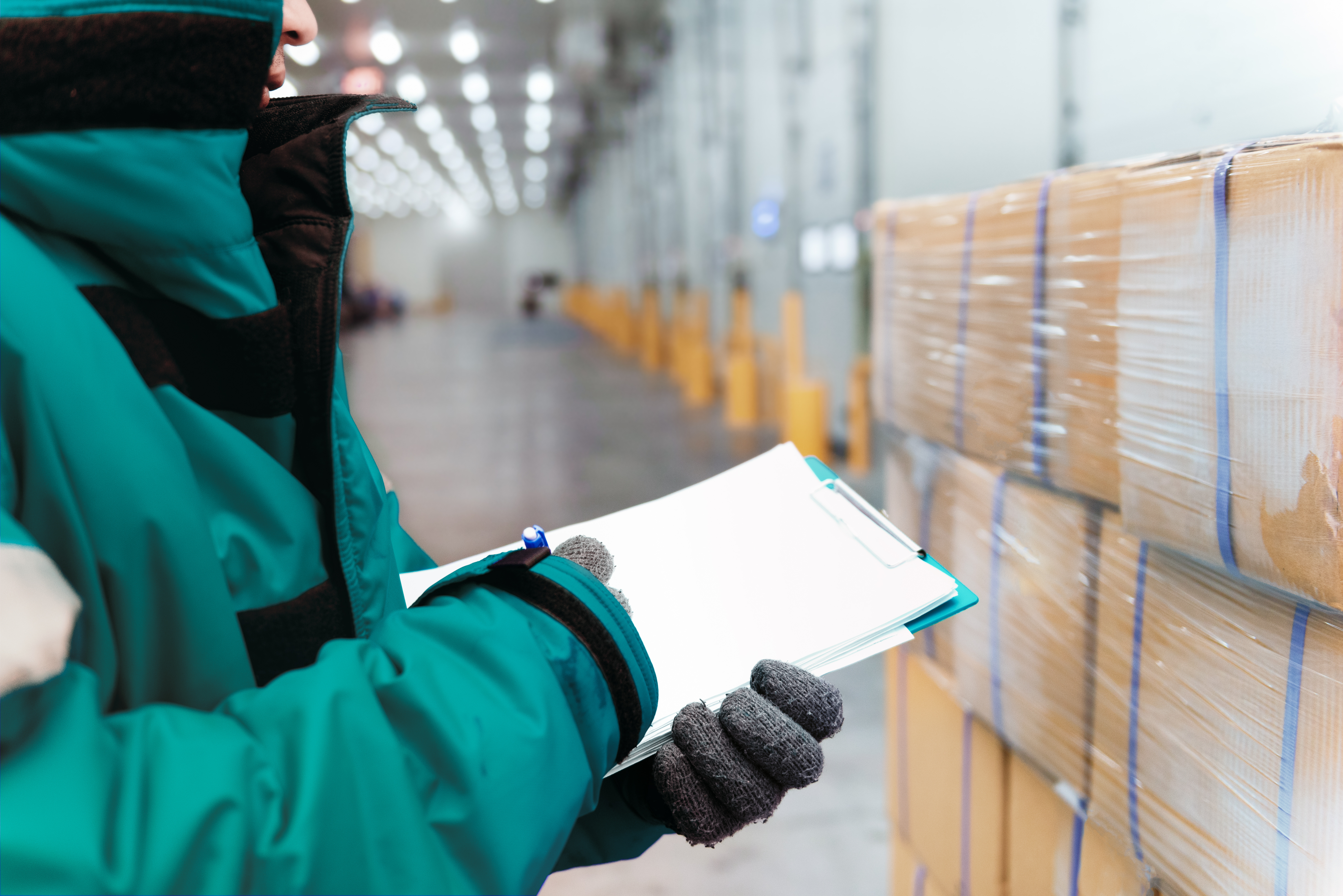 Travailleur avec presse-papiers en train de regarder une palette de boîtes 